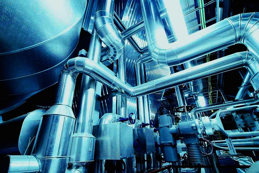 Tubazioni coibentate e valvole con attuatori in una centrale tecnologica.